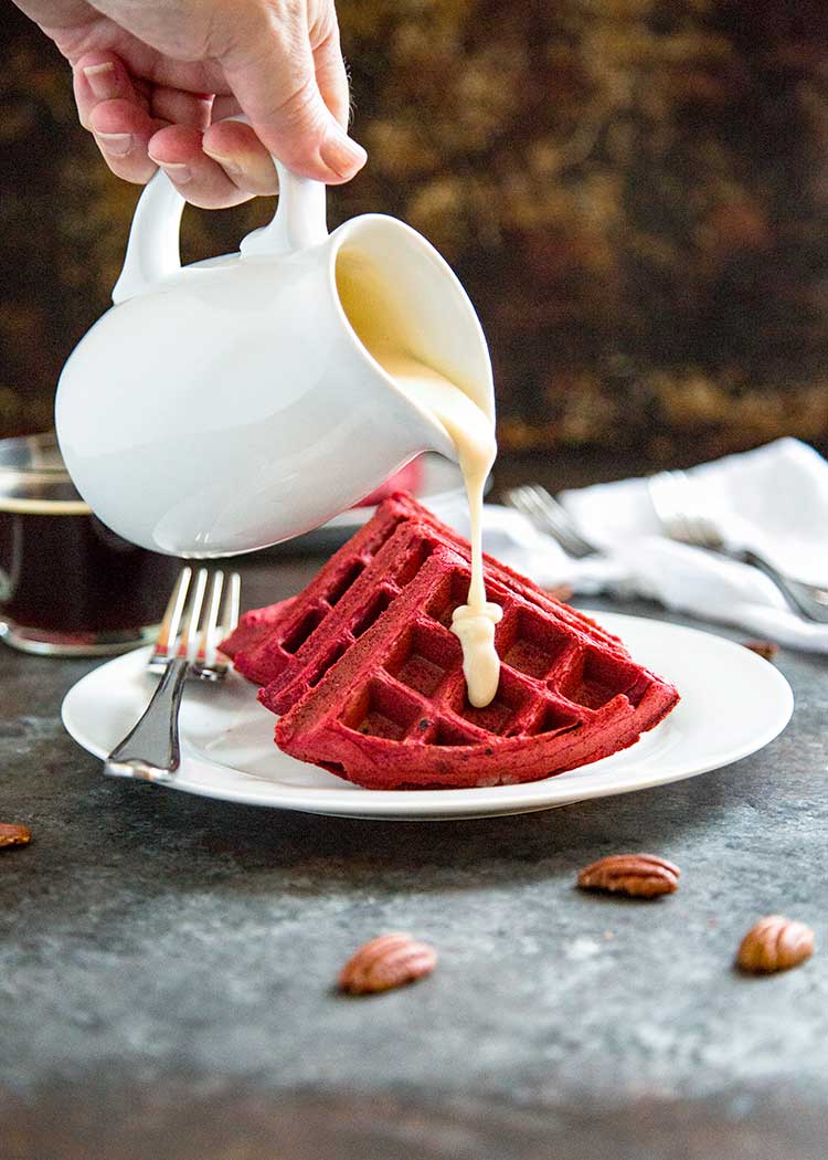 Pouring Cream Cheese Glaze on Red Velvet Waffles.