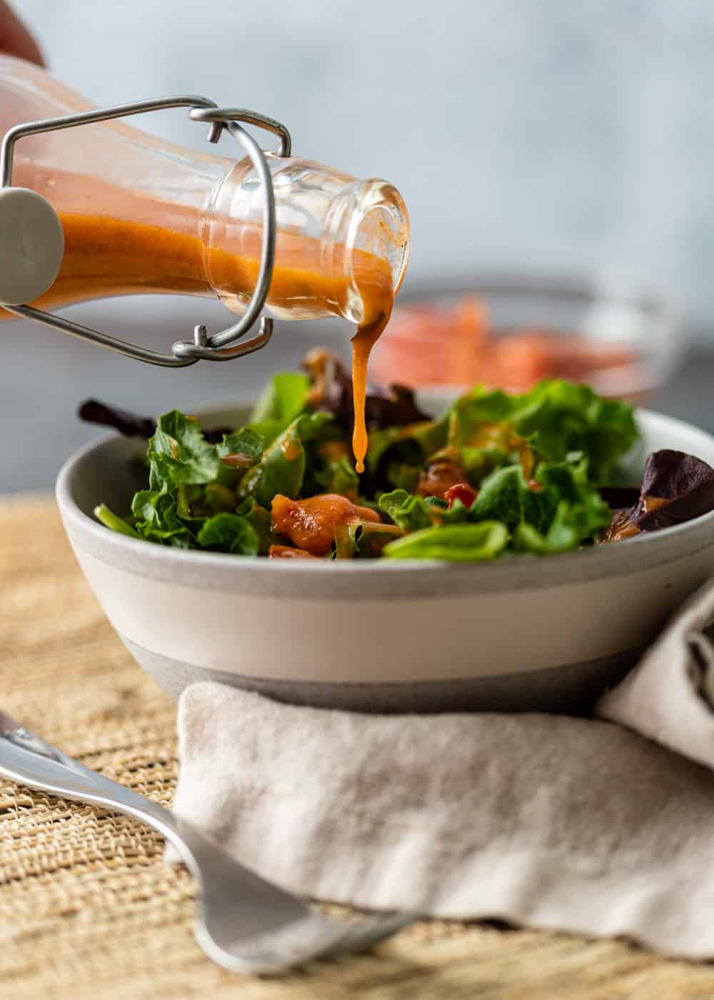 dripping Roasted Tomato Vinaigrette onto salad