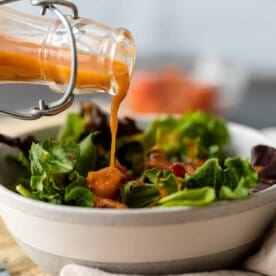 roasted tomato vinaigrette pouring from bottle on salad