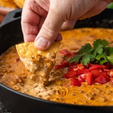 closeup: man dipping chip into skillet of rotel dip