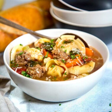 Rustic Pesto Sausage Tortellini Soup hits the spot with tortellini, pan seared Italian sausage, vegetables and a dollop of pesto. All made in 30 minutes! keviniscooking.com