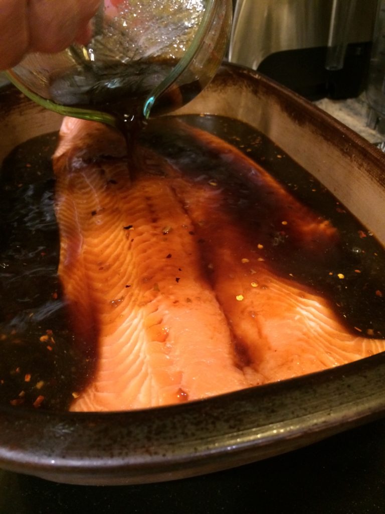 pouring solution of salt water and soy sauce over raw fish