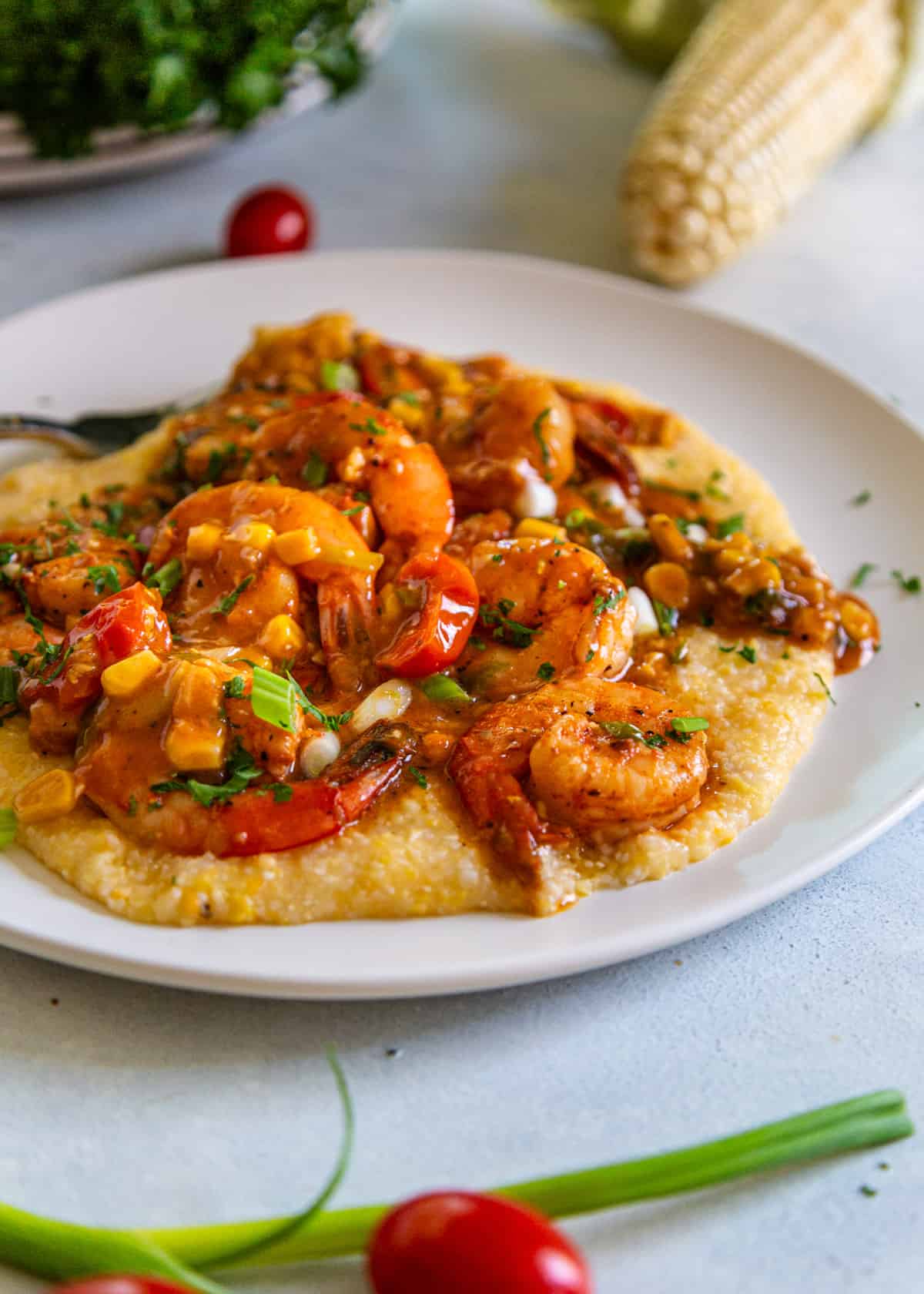 side view: shrimp and grits recipe on a white plate with shrimp and corn showing