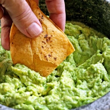 dipping tortilla chip into guacamole without cilantro