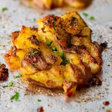 smashed red potatoes with seasoning on baking sheet