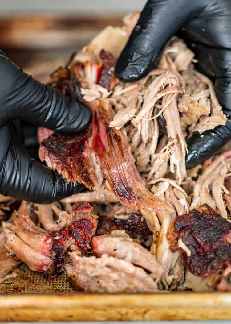 pulling pork with black gloved hands