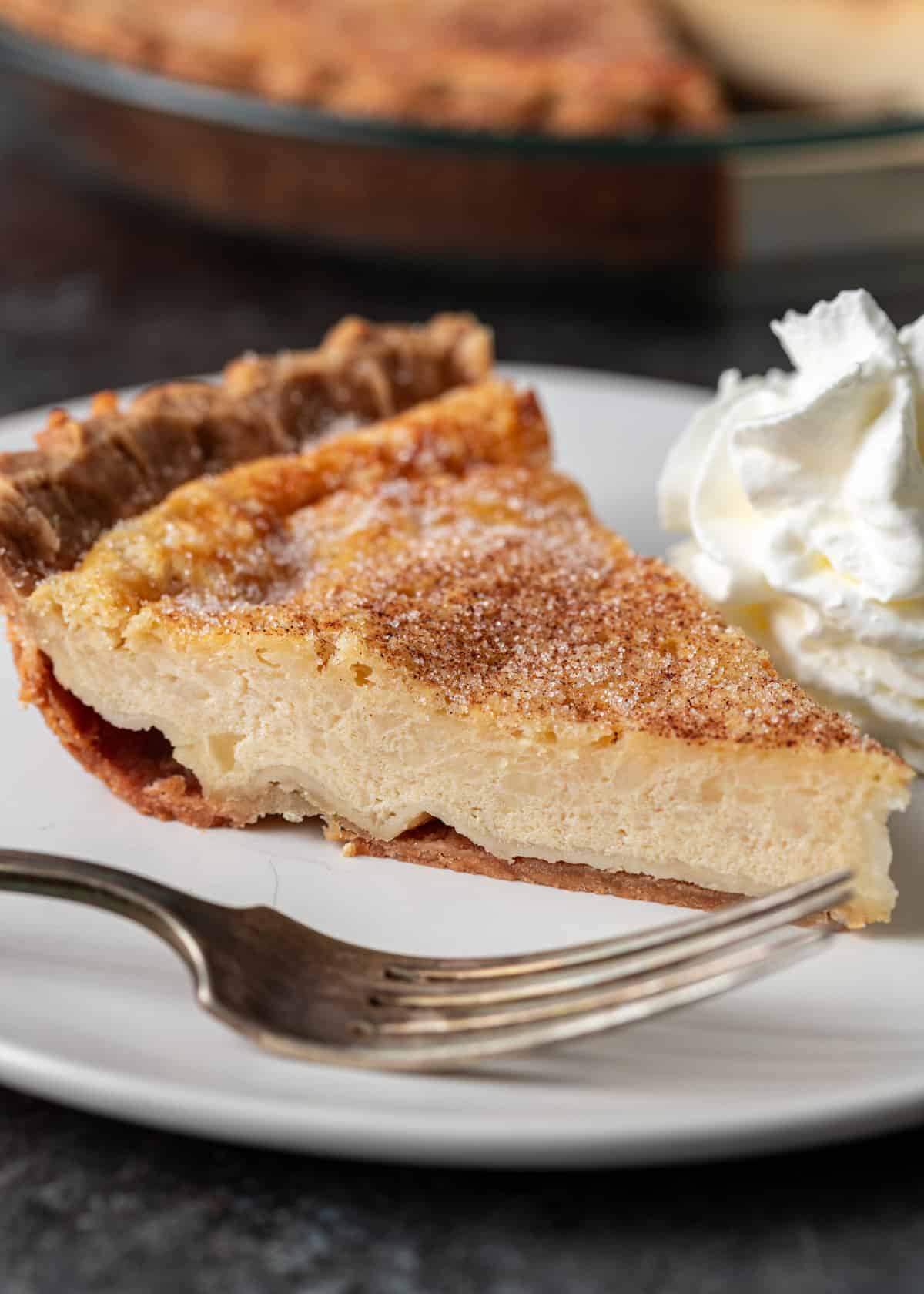 a slice of buttermilk pie on a white plate with the center showing
