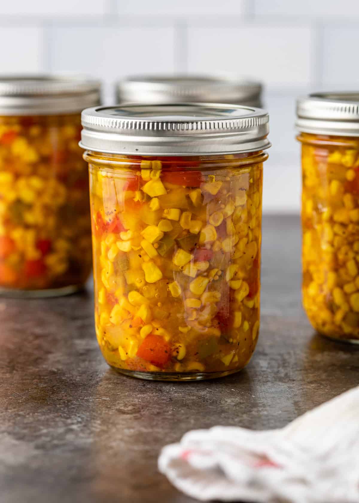 side view: several mason jars full of Southern corn relish on a countertop