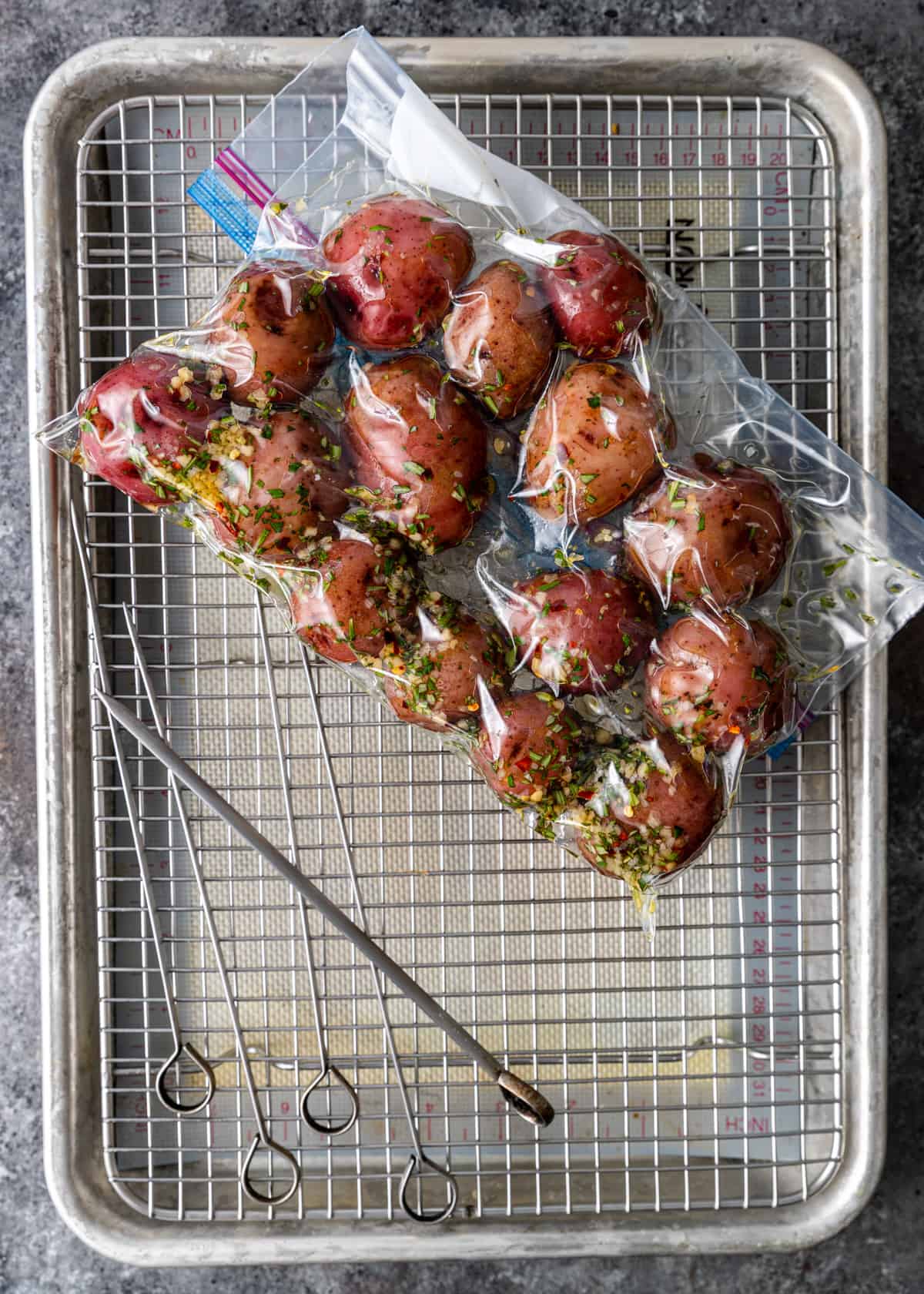 overhead: red potatoes in marinade in a plastic bag on top of a wire rack