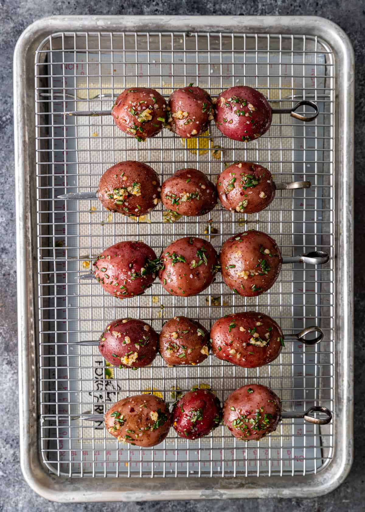 overhead: uncooked red potatoes on skewers on a wire rack