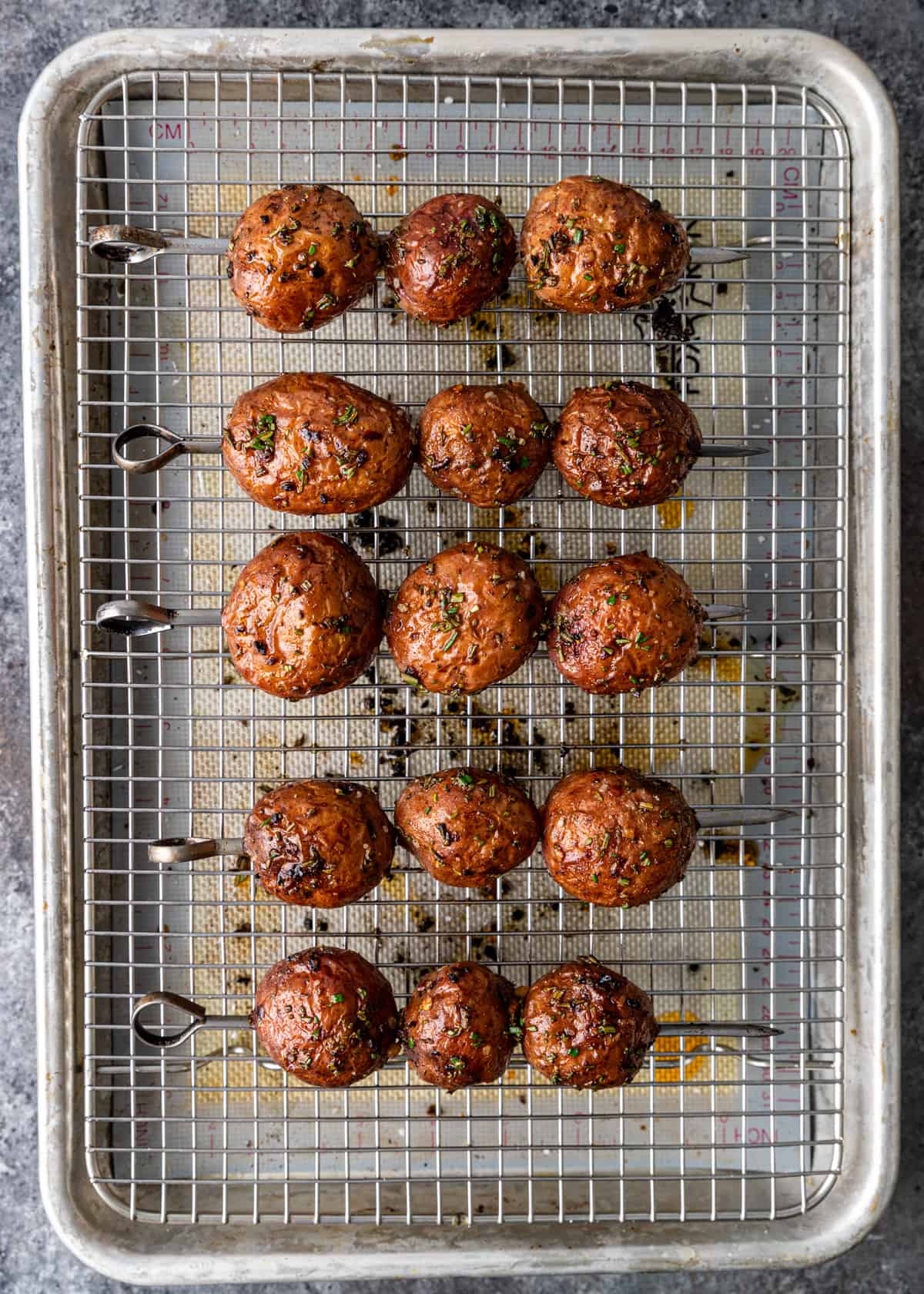 overhead: grilled red potatoes on skewers on a wire rack