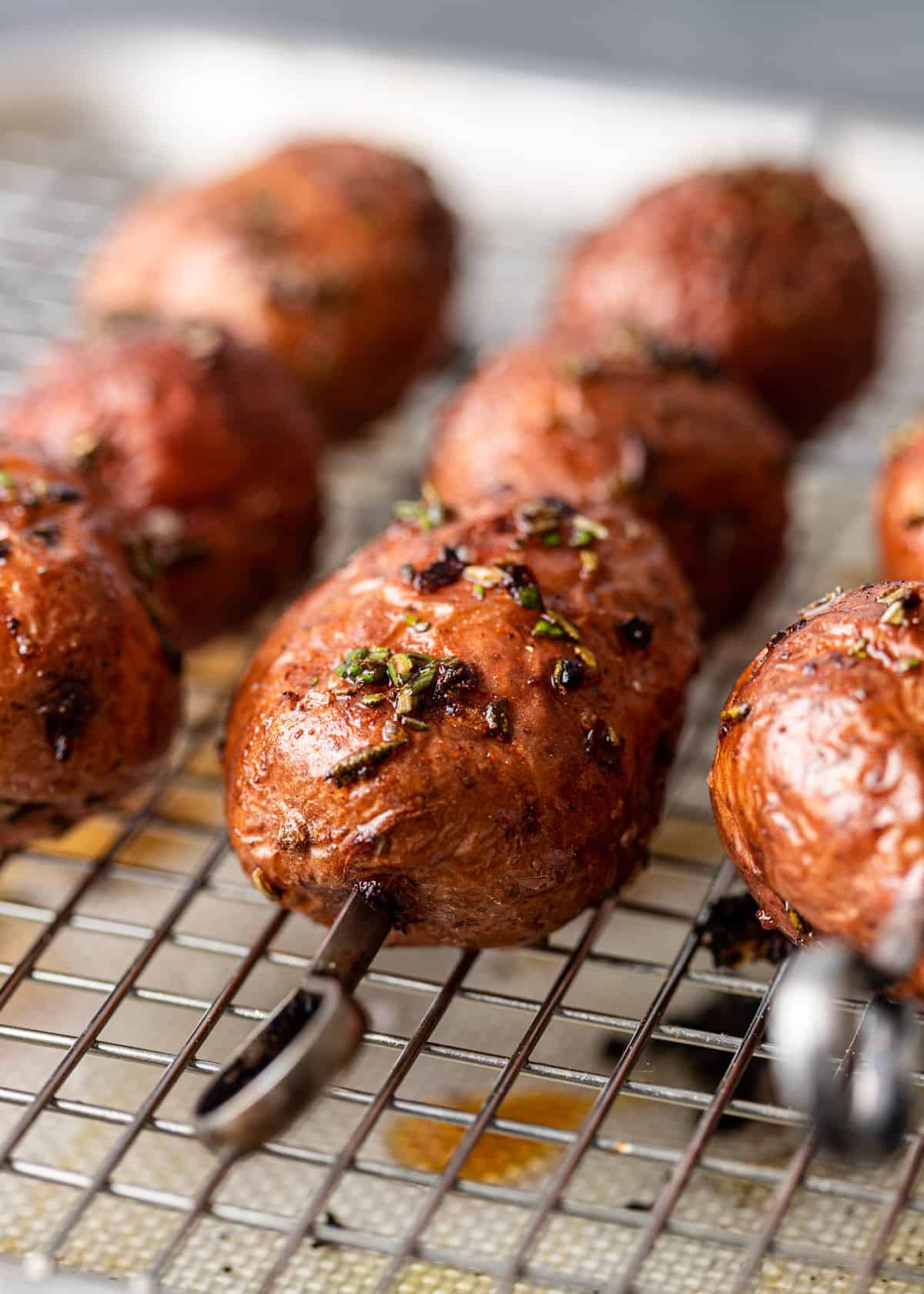 extreme closeup: grilled red potatoes on metal skewers on a wire rack