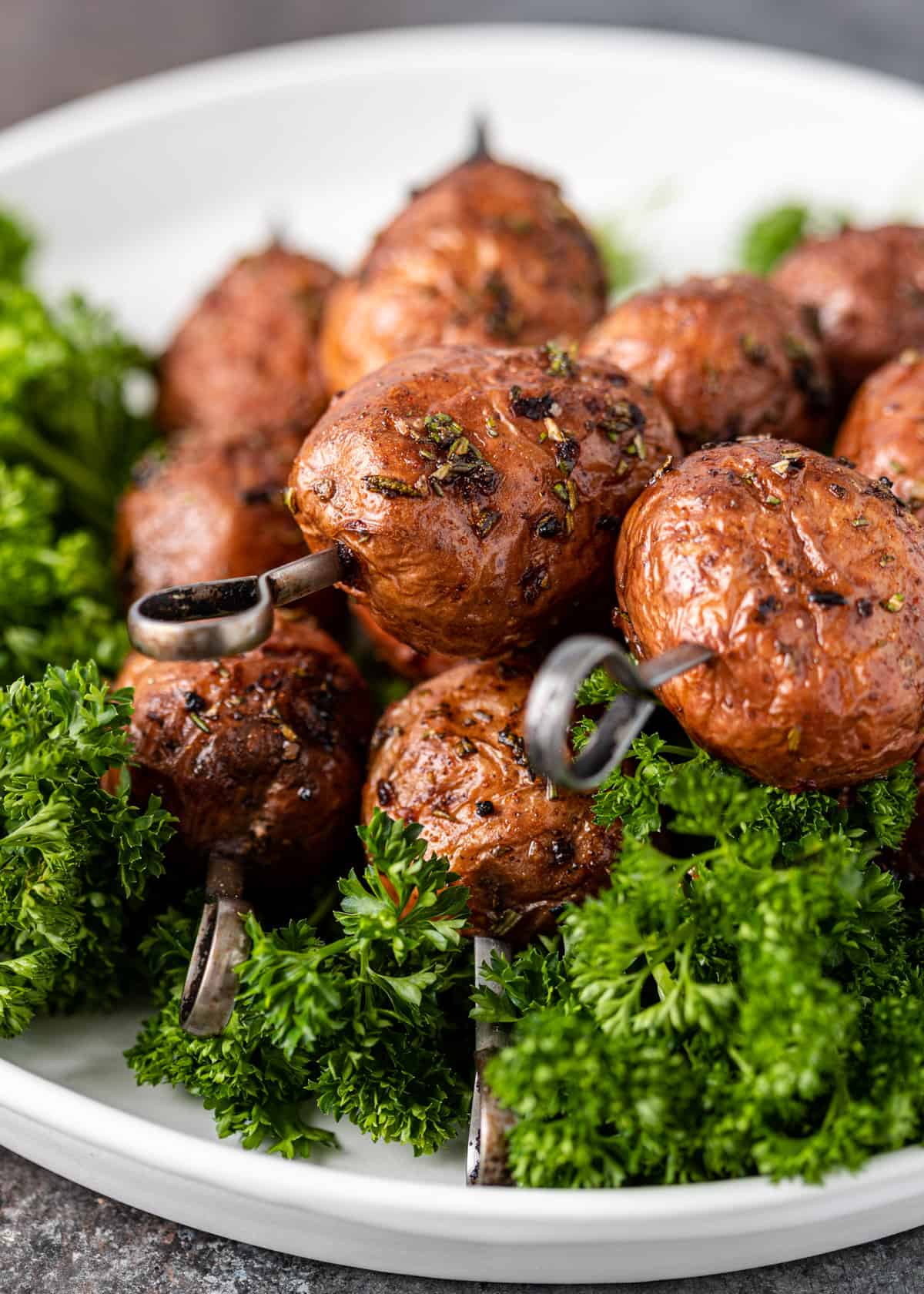 closeup: grilled red potatoes on skewers over fresh herbs