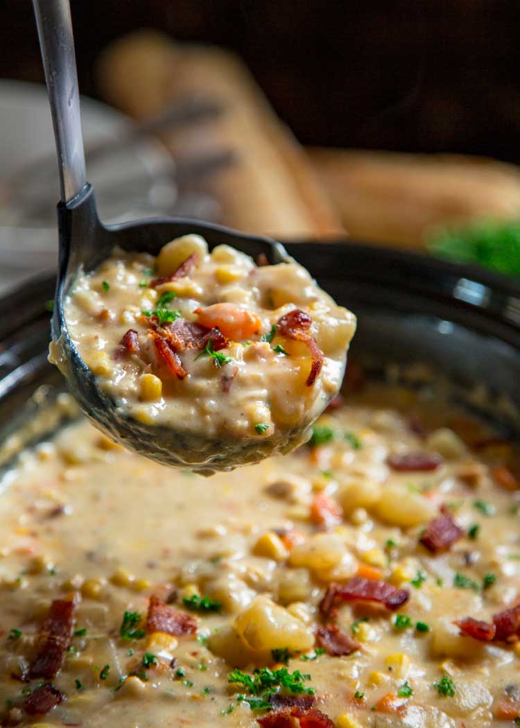 ladle full of thick creamy soup with potatoes and bacon