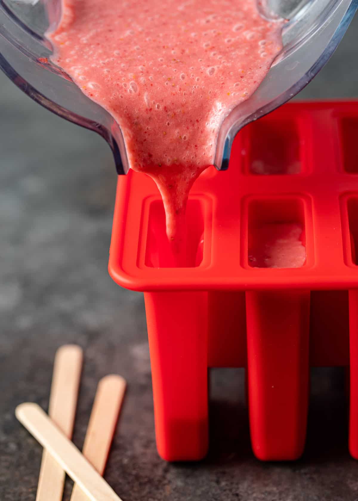 pouring strawberry and cream ice pops into molds