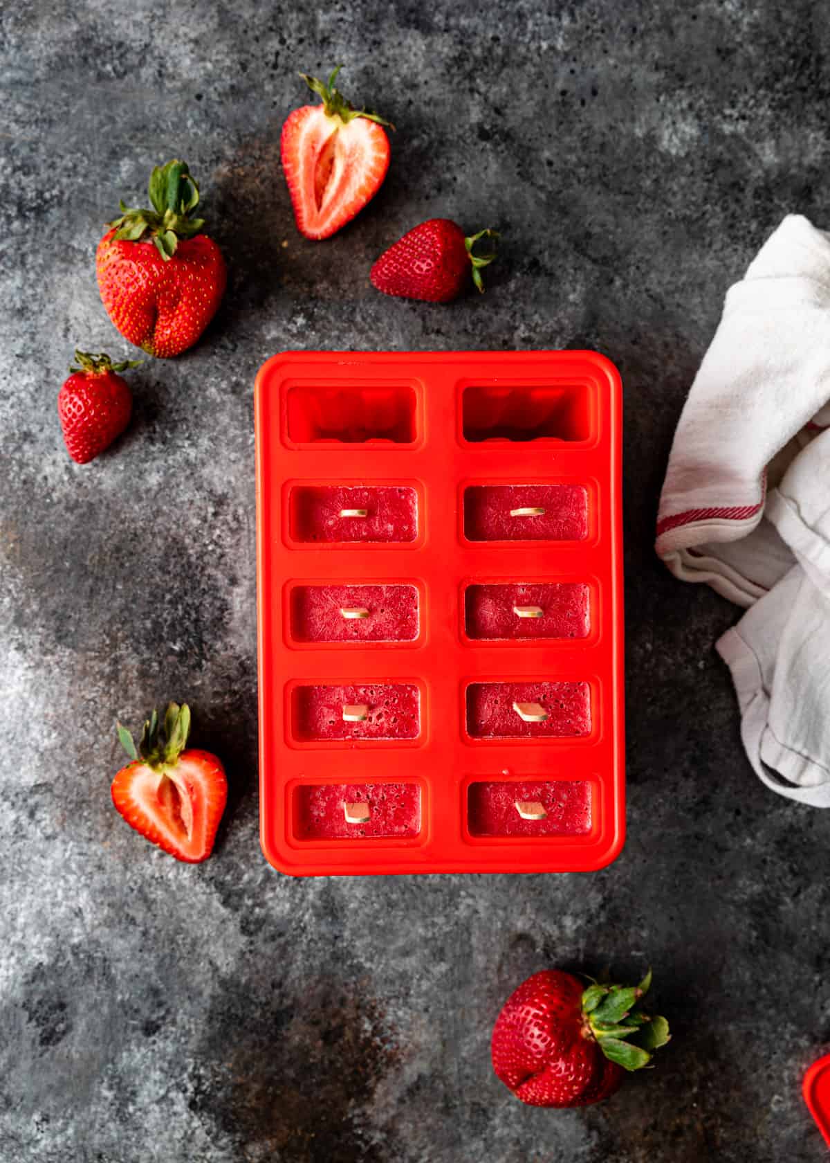 strawberries and cream ice pops in a red mold after freezing