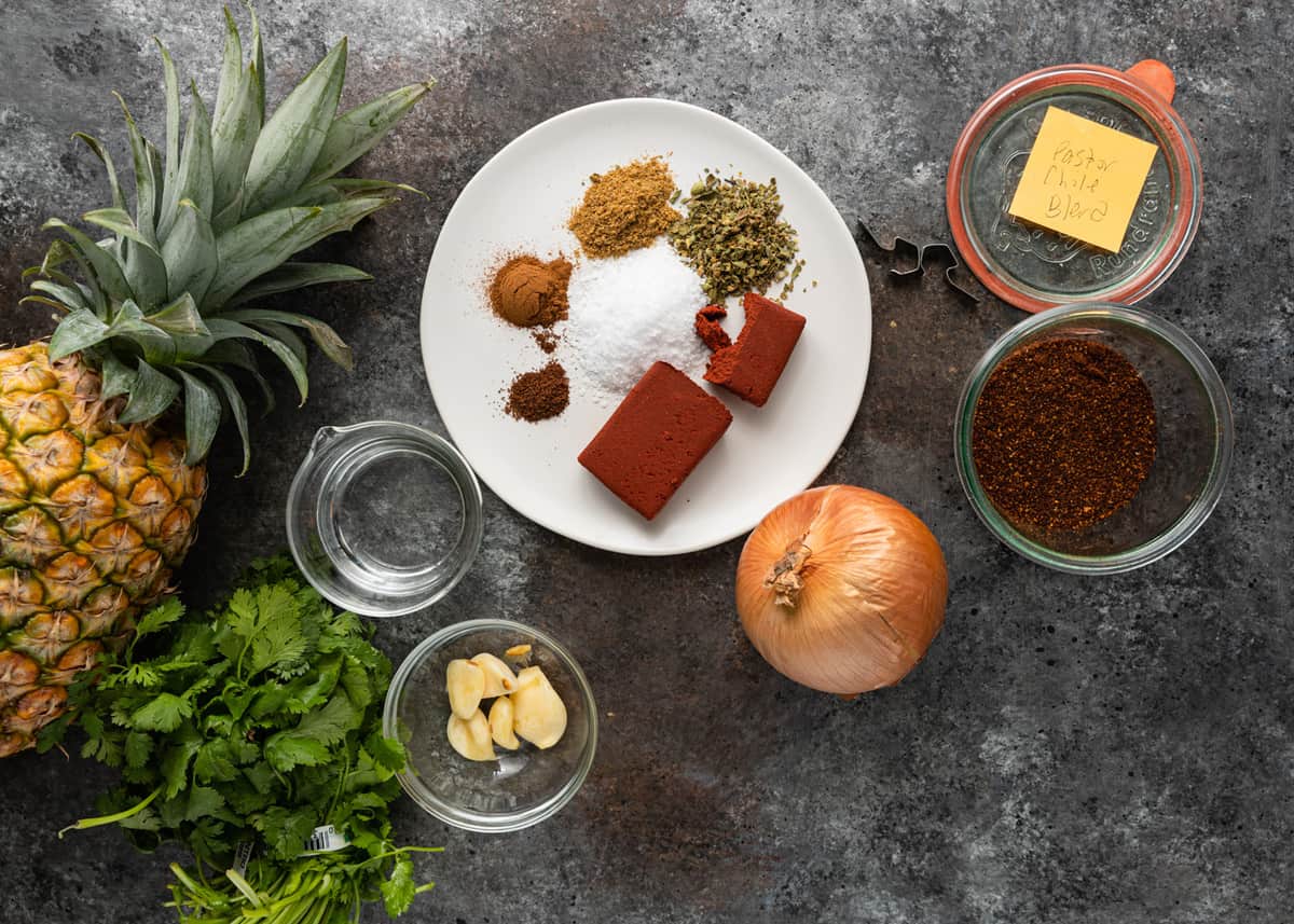 fresh ingredients gathered on a marble cutting board to make tacos al pastor recipe (Mexican pork tacos)