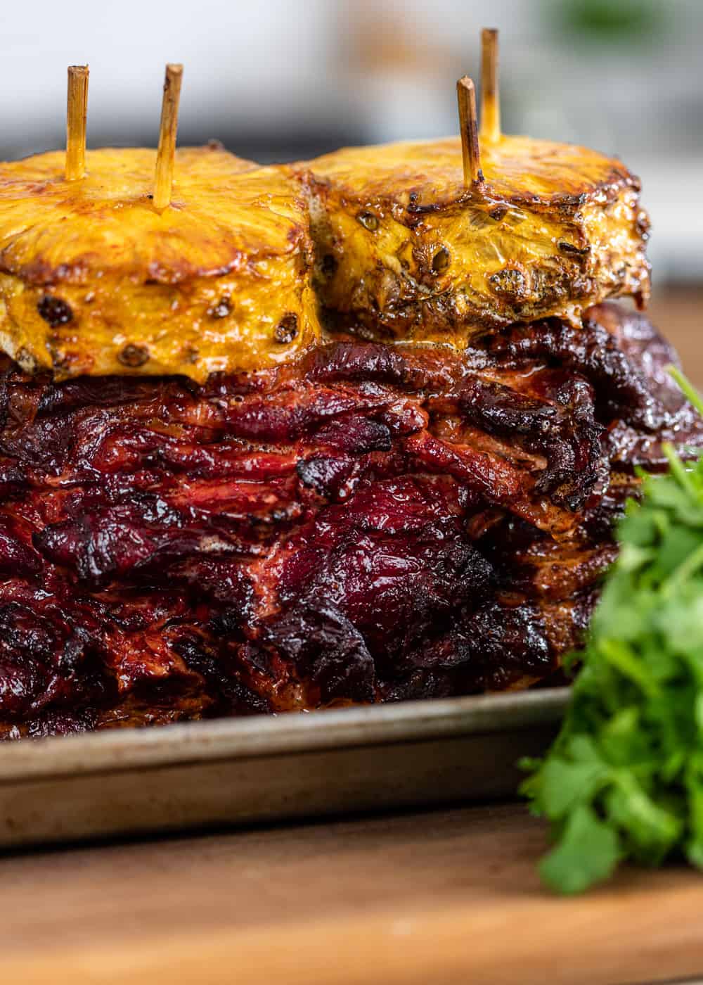 close up of Mexican pork on wooden skewers with fresh pineapple slices on top