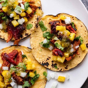 overhead: tacos al pastor meat on tortilla with pineapple and toppings