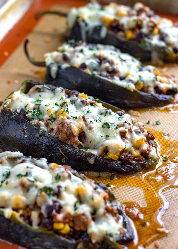 Stuffed green peppers covered in cheese on a baking sheet