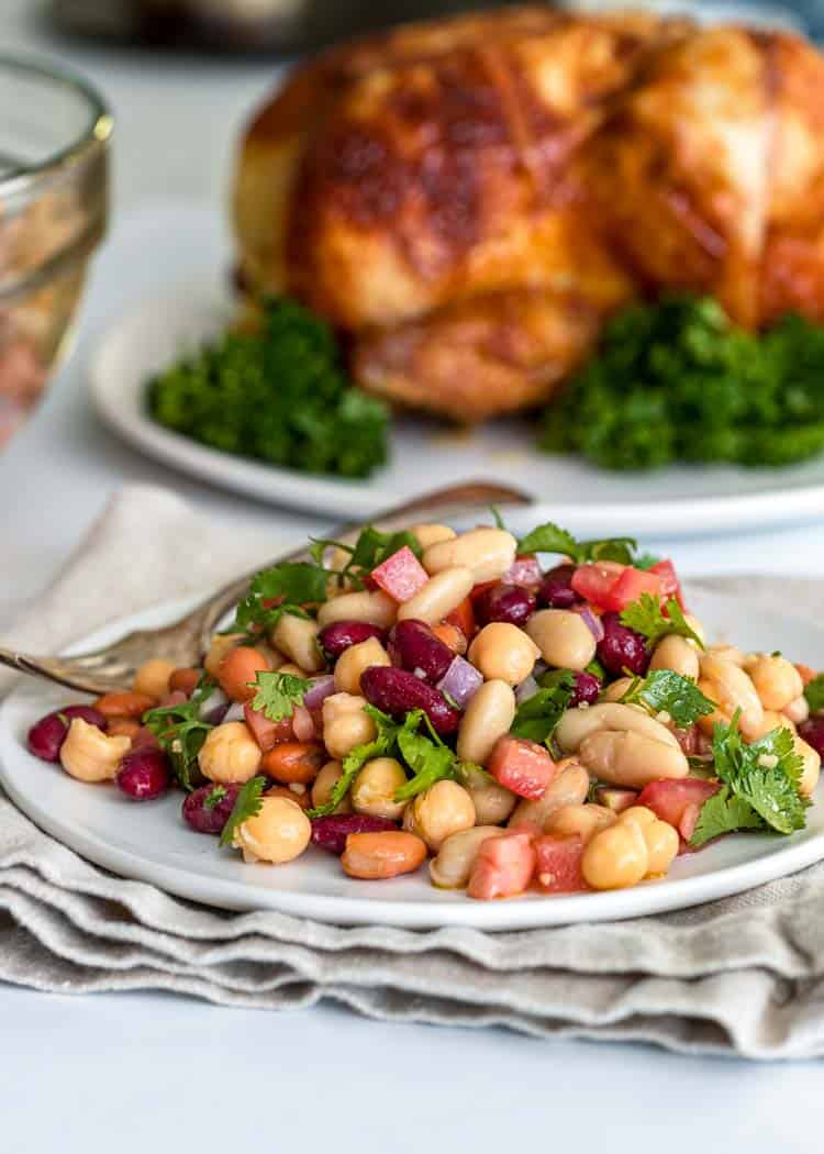 plate of 4 bean salad with roasted chicken in background